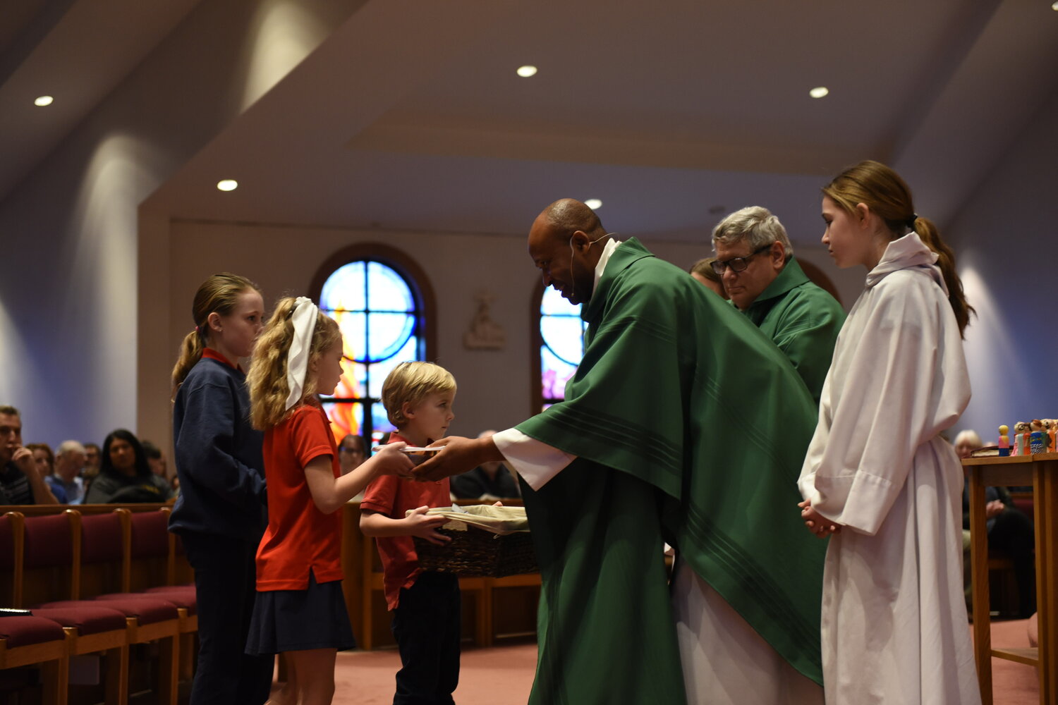 Students of Our Lady of Lourdes Interparish School in Columbia present the gifts at the Offertory to Father Roberto Ike, newly installed pastor of Our Lady of Lourdes Parish, at Mass on Sunday, Jan. 28, the first day of Catholic Schools Week.